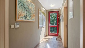 Un couloir avec une porte rouge, une grande carte et un porte-manteau.