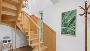 Un escalier en bois avec une rampe, une petite chaise et un tableau encadré accroché au mur.