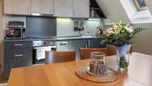 Une cuisine moderne avec des meubles en bois, un four à micro-ondes et une table à manger agrémentée d’un vase de fleurs.