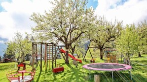 Ein Spielplatz mit Rutsche, Schaukeln und Trampolin.