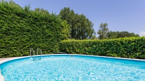 Une piscine d’eau cristalline, entourée d’une végétation luxuriante composée d’arbustes et d’arbres verdoyants.