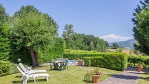 Un jardin avec une piscine, un espace salon extérieur et un chemin en pierre.