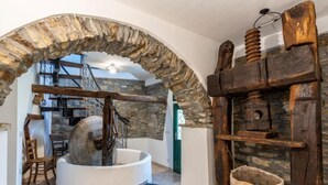 Een rustiek interieur met een stenen boog, een houten molen en een stenen muur.