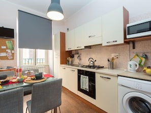 Cocina compacta con comedor, lavadora y microondas.