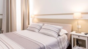 A hotel room with a bed, bedside table, lamp, and curtains.