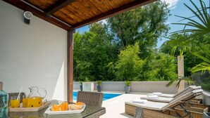 An outdoor patio with a table set for breakfast, a pool, and lounge chairs. - Vacation home Anđela by Interhome (Krk/Dobrinj)