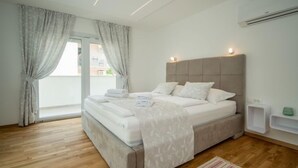 A modern bedroom with a large bed, a sliding glass door to a balcony, and a built-in air conditioning unit. - Vacation home Anđela by Interhome (Krk/Dobrinj)
