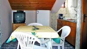 A small dining area with a table, chairs, a television, and a kitchen area. - Apartment Zdenko by Interhome (Ugljan/Kali)