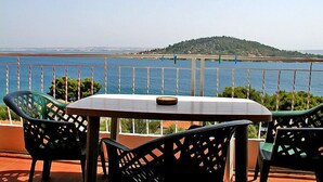 A terrace with a table and chairs overlooking a body of water and a distant hill. - Apartment Zdenko by Interhome (Ugljan/Kali)