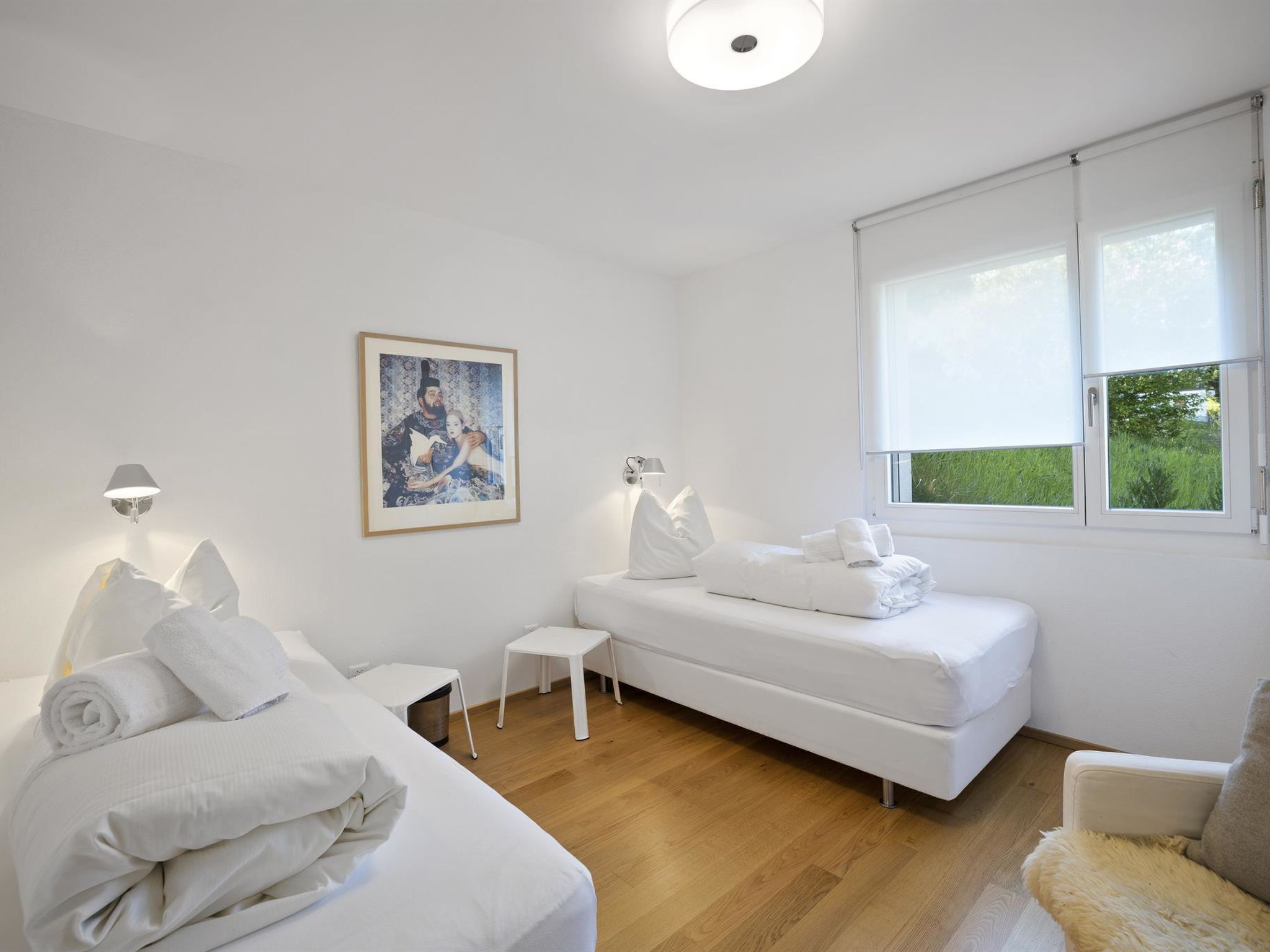 Una habitación de hotel moderna con cama, sofá, una mesita y una ventana con persianas.