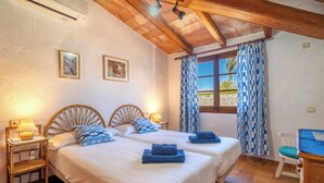 A bedroom with two beds, wooden headboards, a desk, and a chair. - Can Niu by Interhome (Pollença)