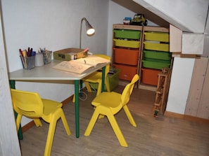 Ein Zimmer mit Schreibtisch, Stühlen, einer Lampe und Stauraum.