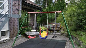 Une aire de jeux avec des balançoires et une surface recouverte de caoutchouc.