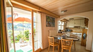 Une cuisine chaleureuse, avec des meubles de rangement en bois et un coin repas comprenant une table et des chaises.