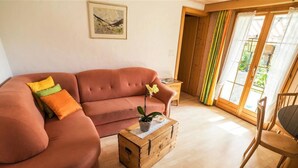Un salon confortable avec un canapé, une table d’appoint en bois et un fauteuil.