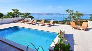 Una piscina en la azotea con sillones de descanso y vistas al mar.