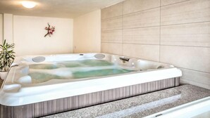Un baño moderno con una bañera independiente, una planta en maceta y un adorno de pared decorativo.