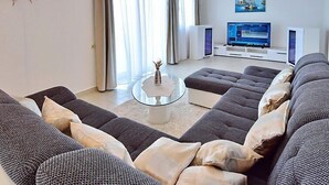 Una sala de estar moderna con un sofá seccional gris, una mesa de centro de vidrio y un televisor de pantalla plana.