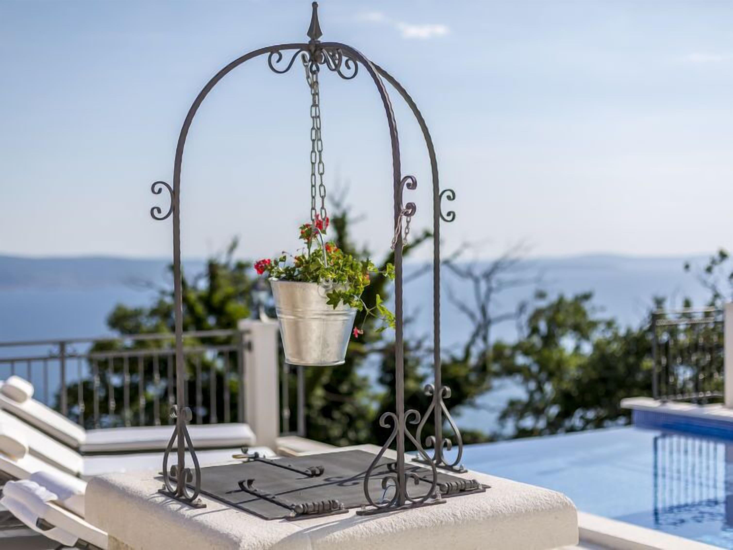 Um vaso pendente de metal com flores perto de uma piscina, com vista para uma paisagem deslumbrante.