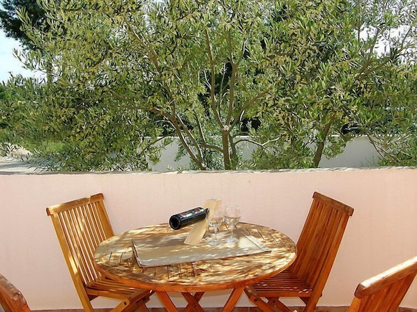 A round glass table with a metal tray, two wooden chairs, and a bottle. - Maslina by Interhome (Vodice)
