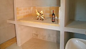 Ein Steinkamin mit einer Weinflasche und einem Glas auf der Kaminablage.