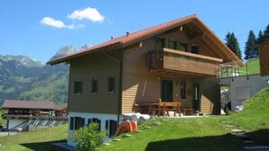 A two-story chalet with a sloped roof, a balcony on the upper floor, and a small porch area. - Panorama, Chalet by Interhome (Zweisimmen)