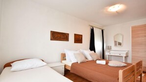 Un dormitorio con dos camas, un aparador de madera, un espejo y obras de arte en la pared.