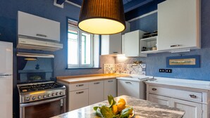 Una cocina moderna con armarios blancos, una isla de mármol y una lámpara colgante.