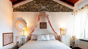 Un dormitorio con techo de piedra, una cama con dosel, un espejo grande y un cartel con el alfabeto enmarcado.