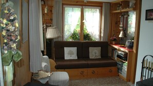 A cozy living room with a brown sofa, a lamp, and a bookshelf. - Bärgchutzli Parterre by Interhome (Adelboden)
