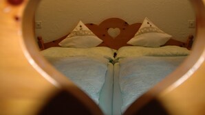 A heart-shaped view of a double bed with pillows and a headboard with a heart design. - Bärgchutzli Parterre by Interhome (Adelboden)