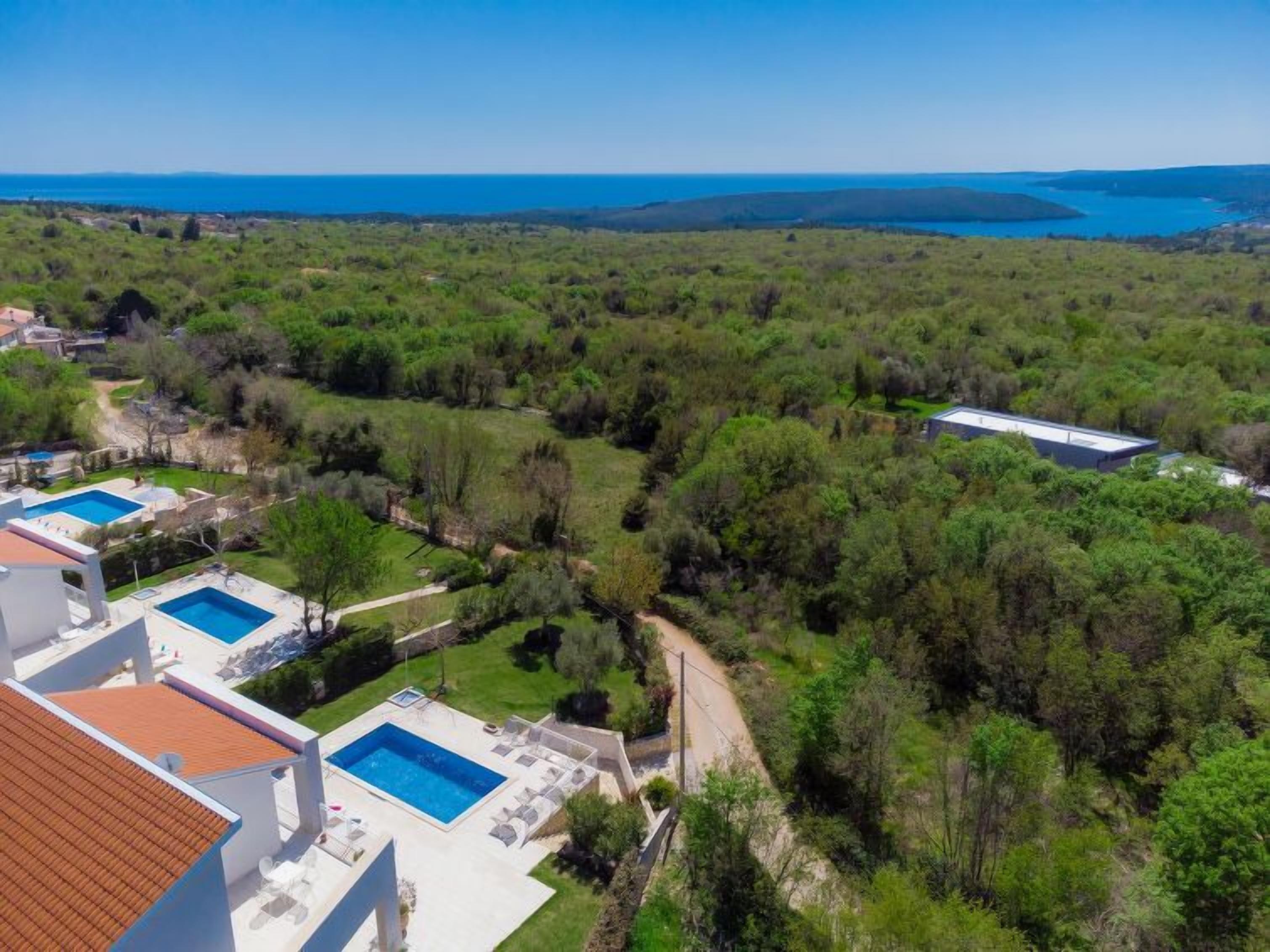 Un quartier résidentiel doté de plusieurs piscines, d’une végétation luxuriante et offrant une vue sur la mer.