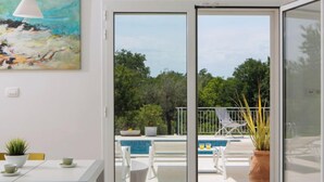 A modern room with a sliding glass door leading to an outdoor area with a pool and seating.