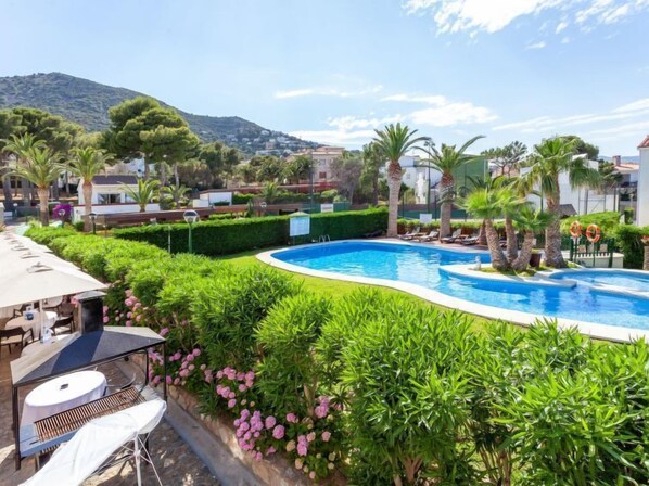 Una piscina rodeada de exuberante vegetación y palmeras, con vistas a un paisaje montañoso al fondo.