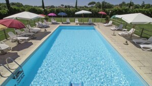 Ein rechteckiger Pool mit klarem Wasser, umgeben von Liegestühlen und Sonnenschirmen.