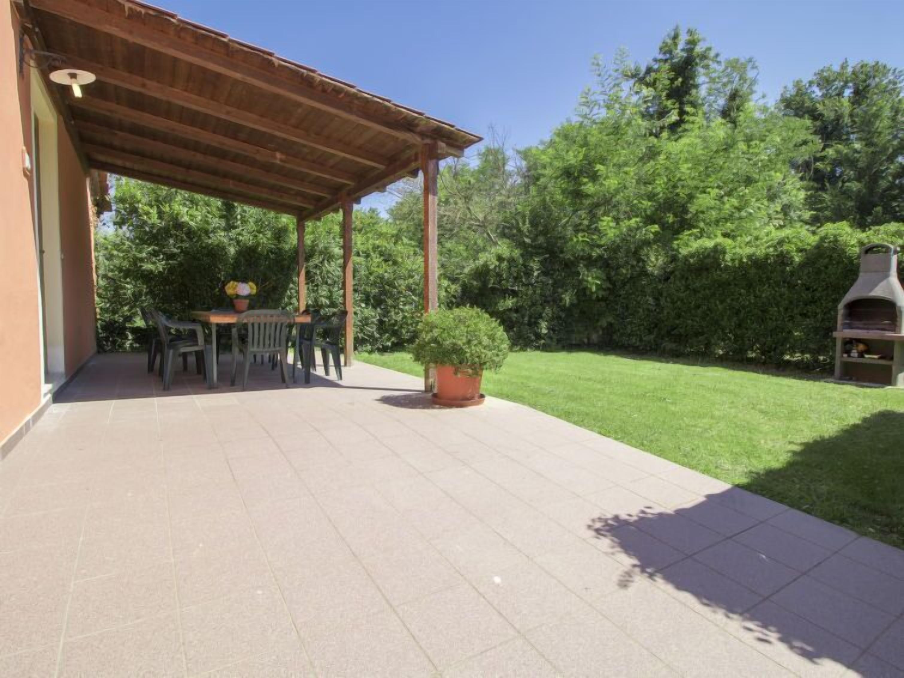 Un patio techado con mesa y sillas, una planta en maceta y una parrilla de barbacoa.
