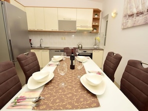 Uma sala de jantar com uma mesa posta para quatro pessoas, equipada com copos de vinho, pratos e talheres.
