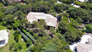 Vue aérienne d’un quartier résidentiel avec une grande maison entourée d’une végétation luxuriante.