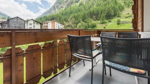 A balcony with wooden railings, two wicker chairs, and a table. - Haus Adora by Interhome (Saas-Almagell)
