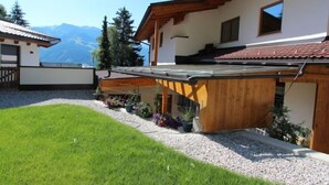 A modern house with a wooden deck, a well-maintained lawn, and a mountain backdrop. - Apartment Anita by Interhome (Zell am Ziller)