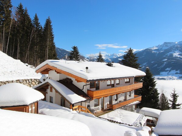 A multi-story chalet with a wooden balcony, surrounded by snow-covered mountains and trees. - Apartment Anita by Interhome (Zell am Ziller)