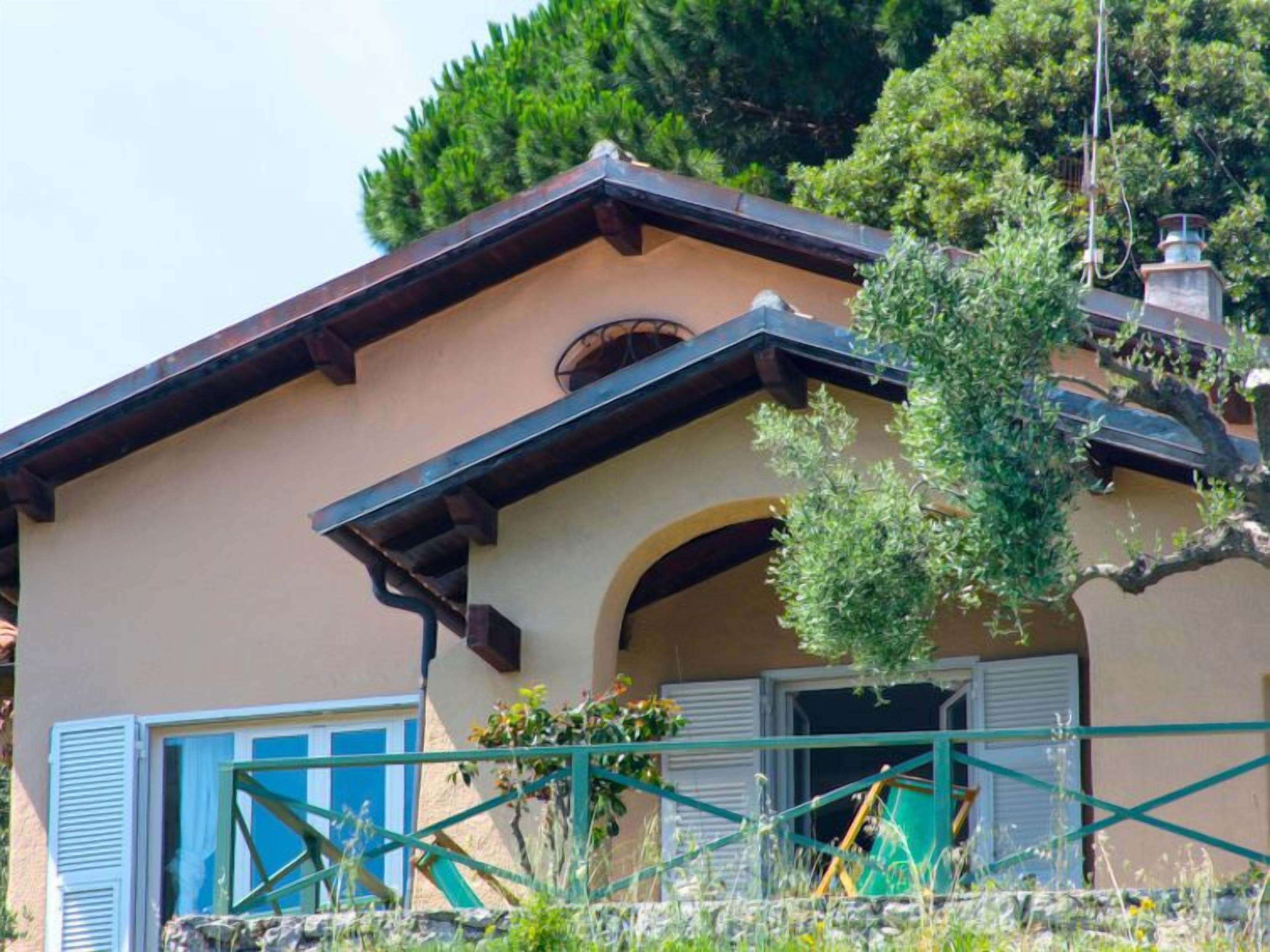 A two-story building with a beige facade, dark brown roof, and a small arched entrance.