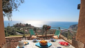 Ein Frühstückstisch mit Meerblick, Terrassenstühle und einer Brüstung.