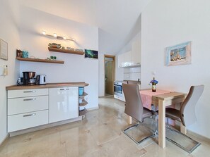 Una cucina moderna con zona pranzo, che include una macchina da caffè, una bottiglia di vino e una TV appesa al muro.
