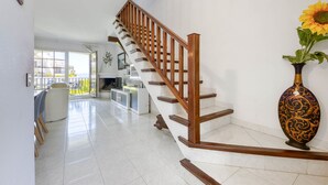 Un intérieur moderne agrémenté d’un escalier en bois, d’une cheminée et d’un grand vase contenant un tournesol.
