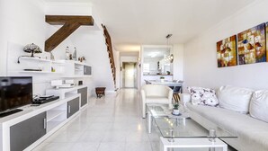 Un salon moderne avec un canapé, une table basse, un téléviseur et un escalier.