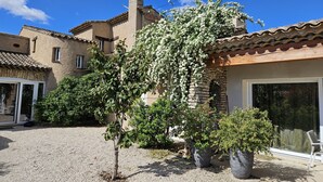 Ein Innenhof mit Kiesboden, einem kleinen Baum und einem Gebäude mit Ziegeldach und Steinmauern.