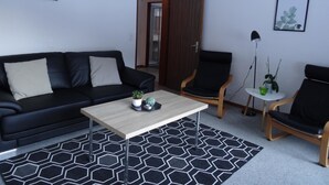 Ett modernt vardagsrum med en svart lädersoffa, ett träbord och två svarta fåtöljer.
