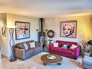 A living room with two sofas, a coffee table, a fireplace, and wall art. - Collina Verde B by Interhome (Ascona)