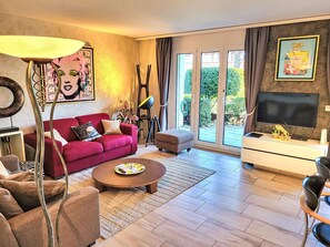 A modern living room with a red sofa, a coffee table, and a television. - Collina Verde B by Interhome (Ascona)